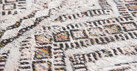 Closeup detail of rug with Morrocan nomad pattern in white tones with grey detail.