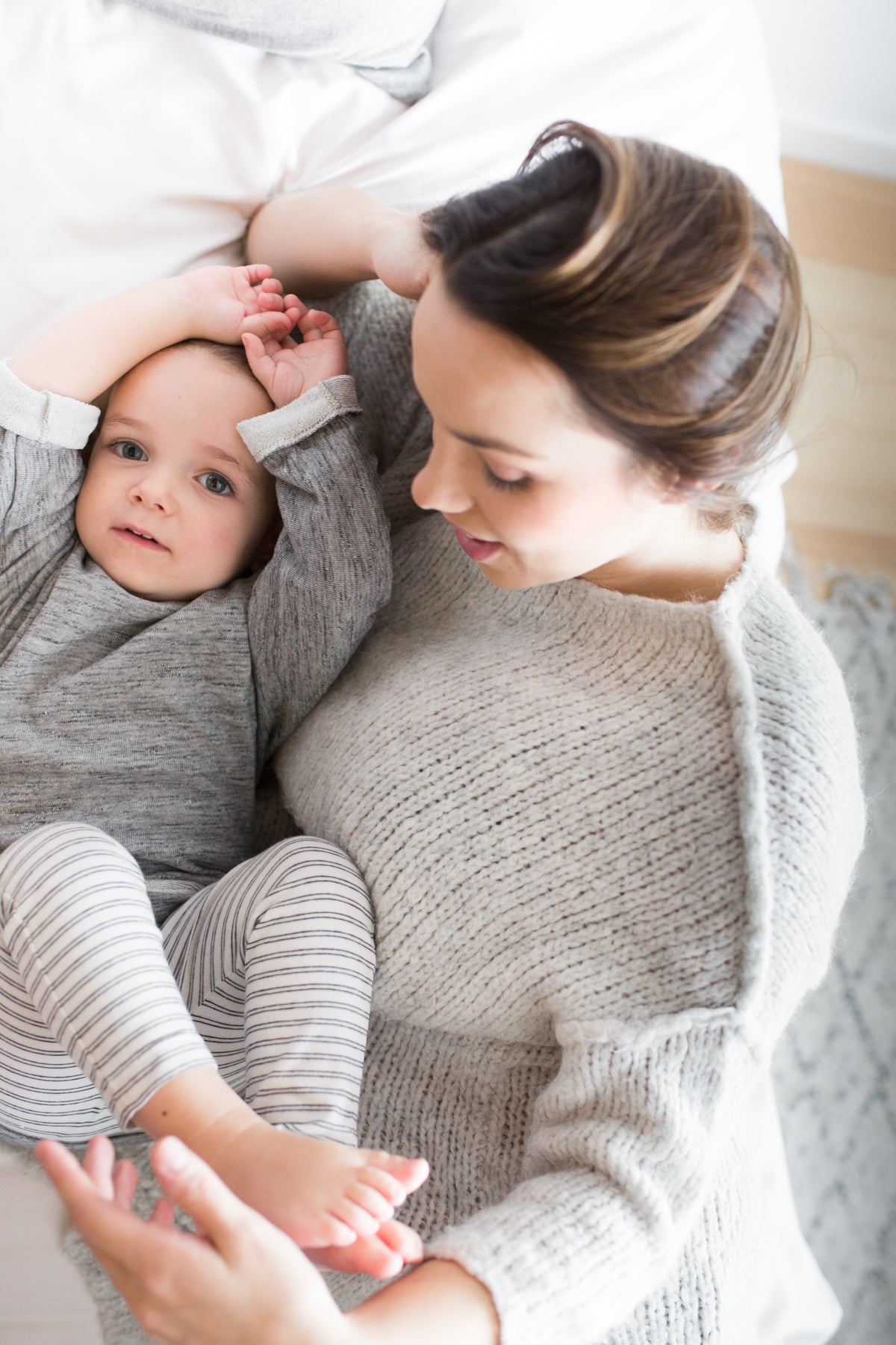 Mother and baby lying down - baby in grey and white stripe leggings