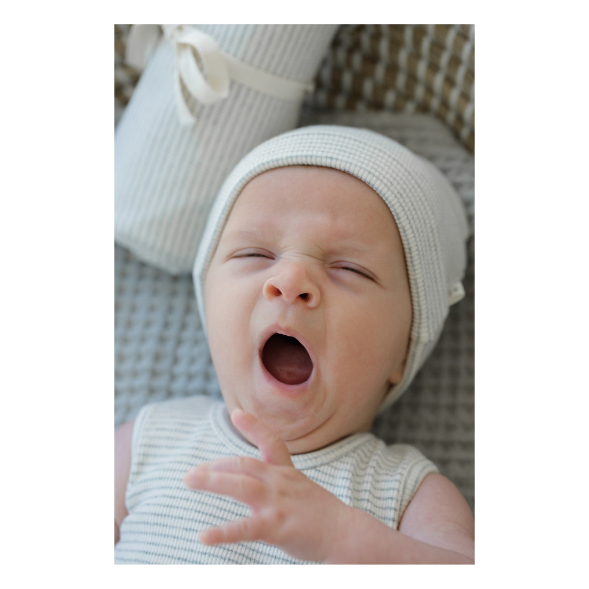 Closeup of cute yawning baby with organic cotton beanie on